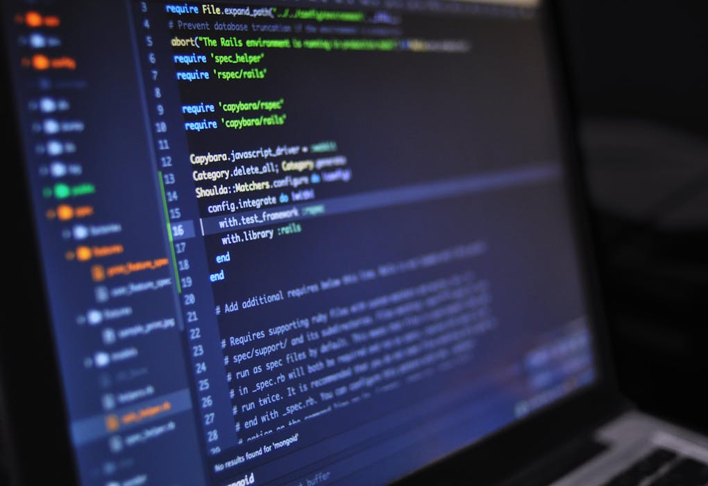 Close-up of a computer screen displaying programming code in a dark environment.