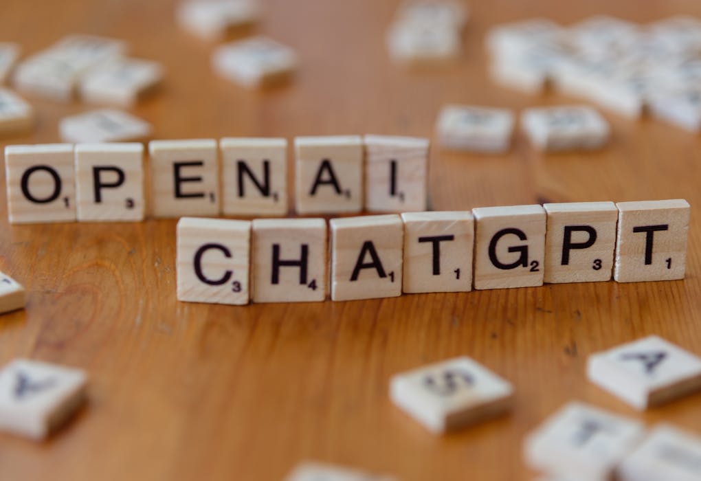 Wooden letter tiles spelling 'OPENAI CHATGPT' on a wooden surface, focused image.